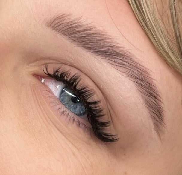 Close-up of a person's eye with long eyelashes and well-groomed eyebrow.