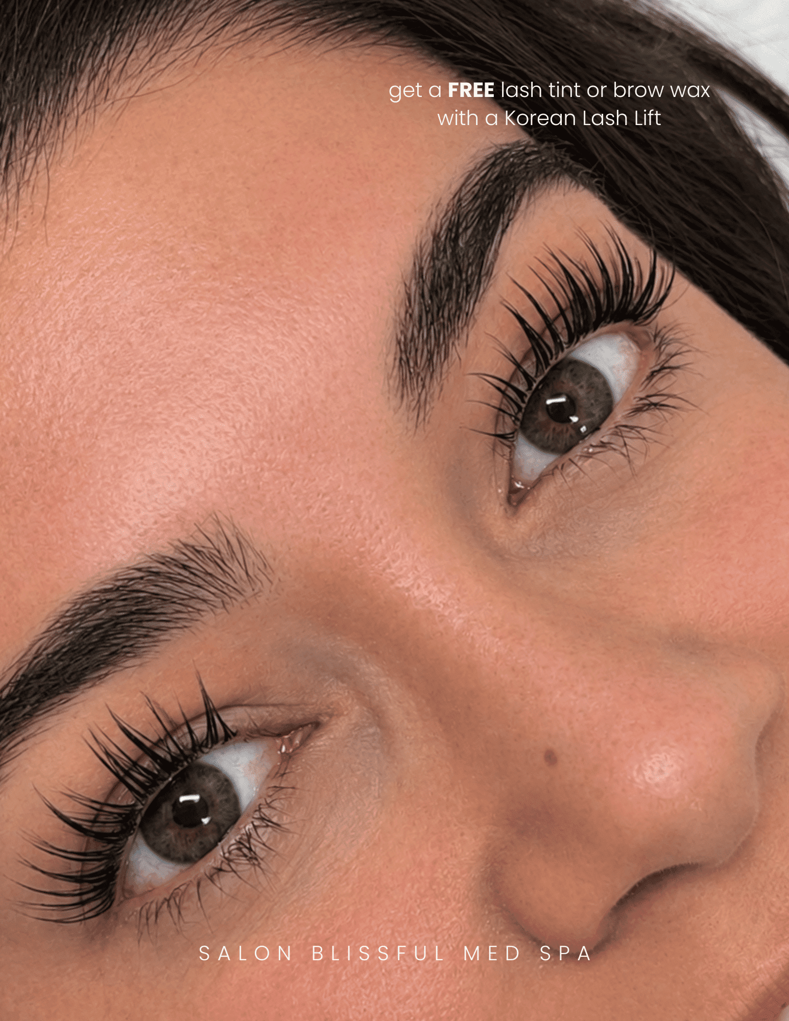 Close-up of a woman's eyes with long lashes. Text: Free lash tint or brow wax offer.