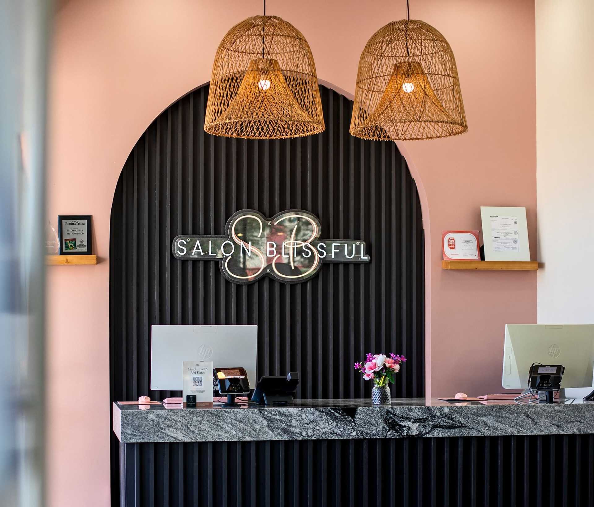 Reception area of Salon Blissful with neon sign and wicker pendant lights.